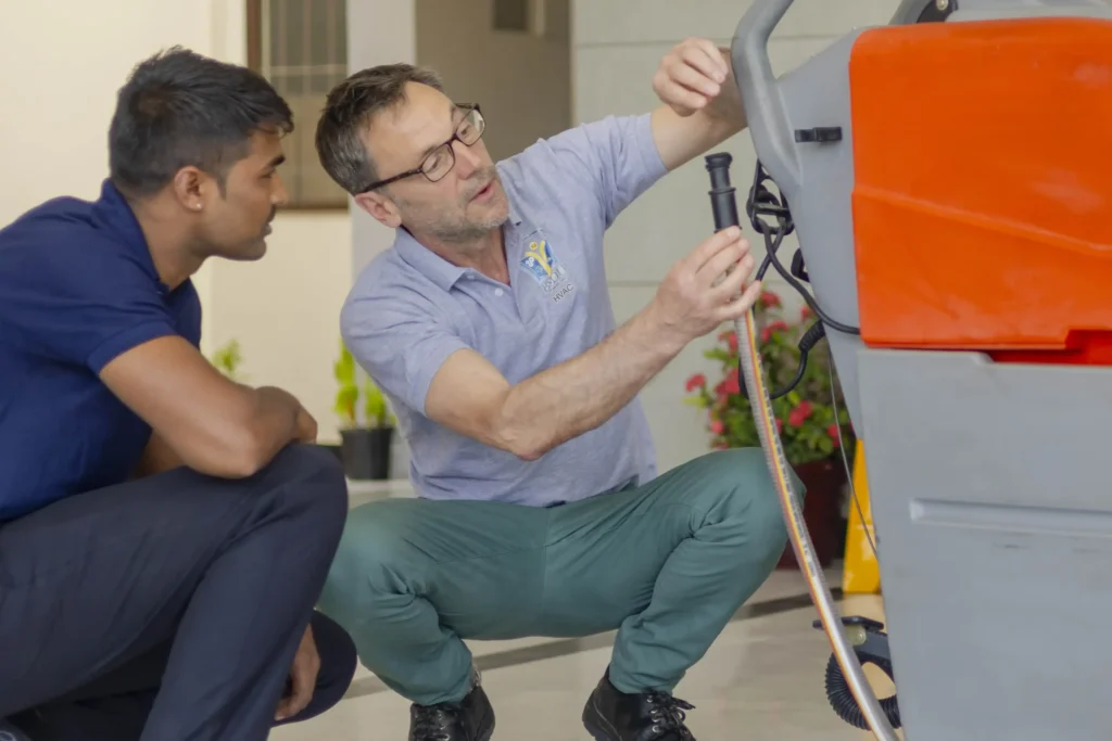 BVoc in Facility Management: A trainer explains the handling of a machine to a student