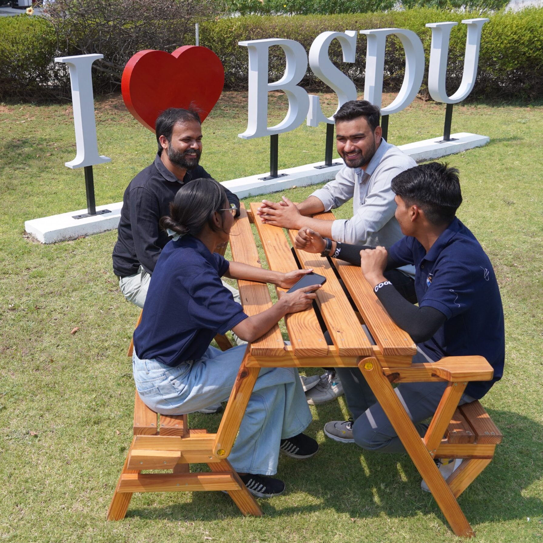 Studierende diskutieren gemeinsam an einem Tisch über Studieninhalte und Projekte in einer kollaborativen Lernumgebung.