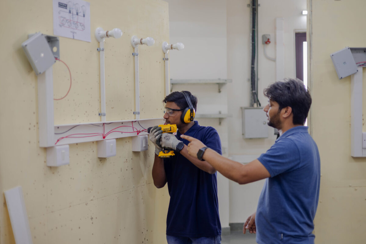 A trainer providing hands-on instruction to a student in a real work setting at Bhartiya Skill Development University, Jaipur.