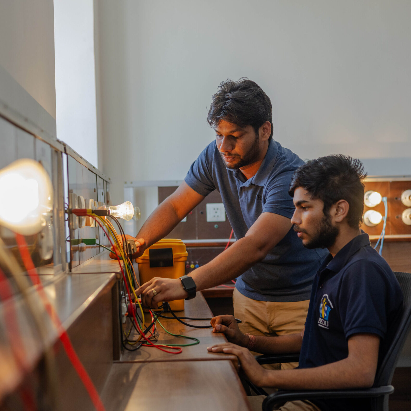 Ein Trainer erklärt einem Studenten in einem Elektrolabor der Bhartiya Skill Development University (BSDU) den Aufbau und die Funktionsweise einer elektrischen Schaltung.