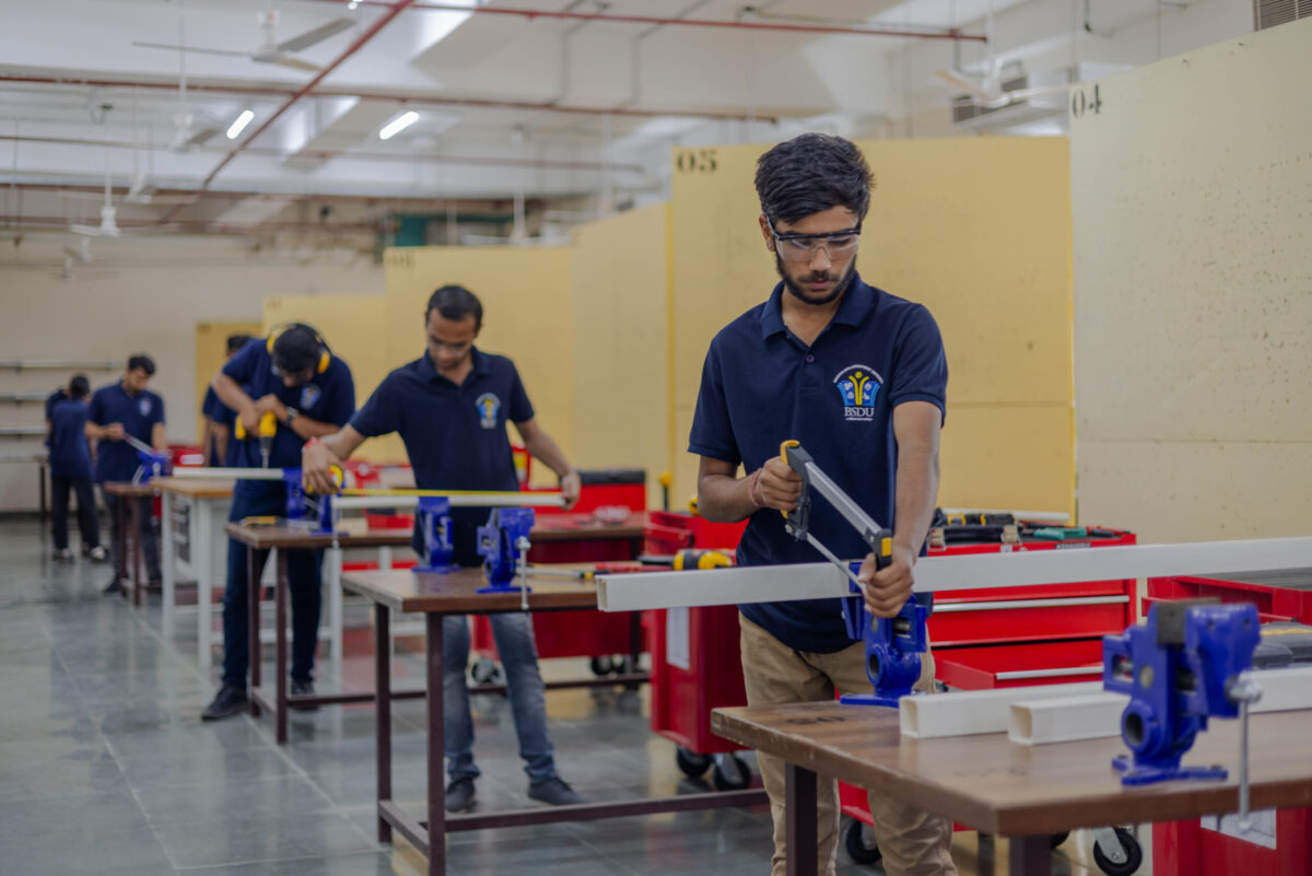 Studierende der Bhartiya Skill Development University führen praktische Metallarbeiten an Werkbänken aus und bearbeiten Werkstücke unter realen Ausbildungsbedingungen.