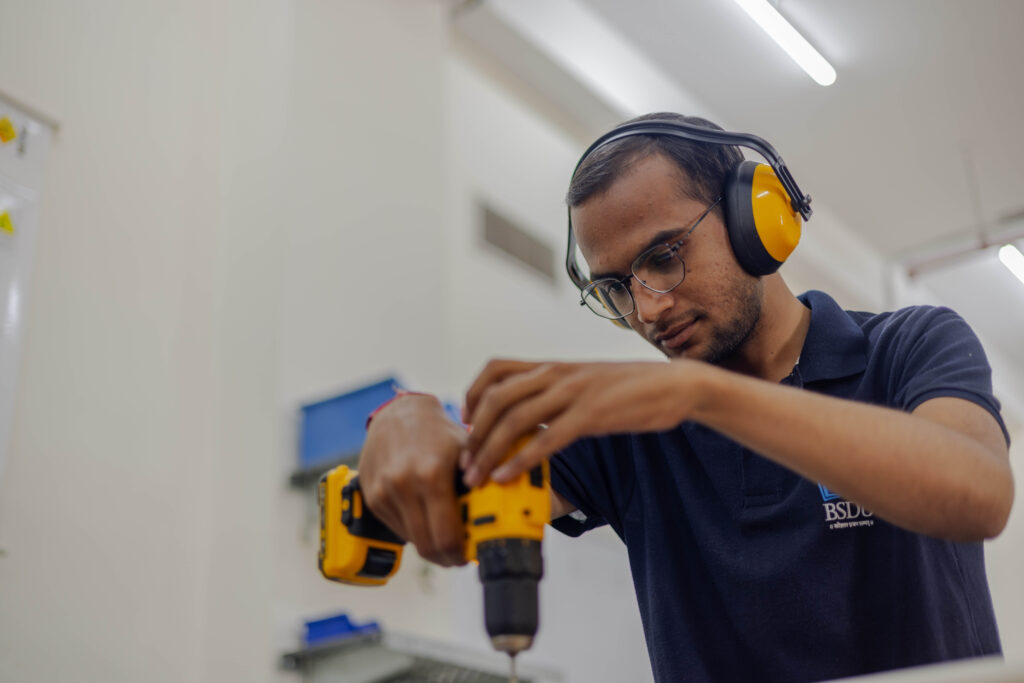 Student der Bhartiya Skill Development University arbeitet konzentriert mit einem Akkuschrauber und führt eine präzise Montageaufgabe unter realen Trainingsbedingungen aus.